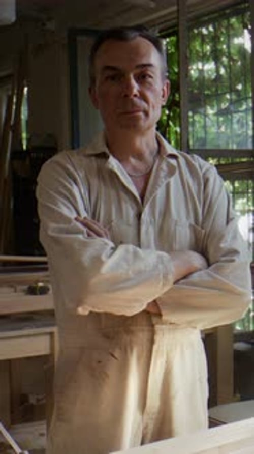 Carpenter Stands in Workshop Evaluating Restoration Project