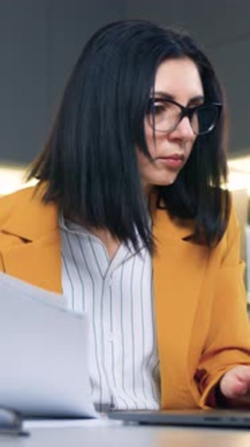 Focused Woman Works with Laptop and Documents