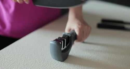 Gros plan d'un couteau à aiguiser pour femme avec aiguiseur de couteaux sur la table de cuisine Affûtage de couteaux