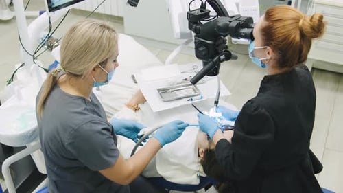Das zahnärztliche Personal führt die Patientenbehandlung in einer Klinik mit einem Mikroskop durch, um eine präzise Untersuchung zu gewährleisten