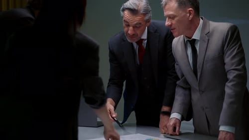 Businessmen Reviewing Charts in a Workplace Meeting