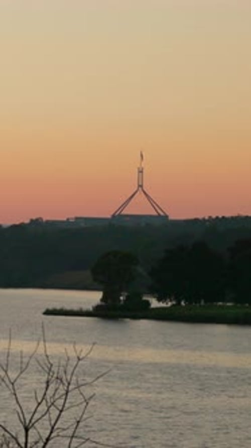 Vertical Australian Parliament House pre-dawn red glow Lake Burley Griffin foreground Canberra dawn