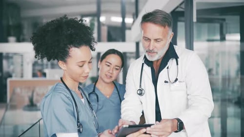 Medical Team Examining Data on Tablet in Hospital