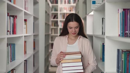 Young Woman Holds Books in University Library