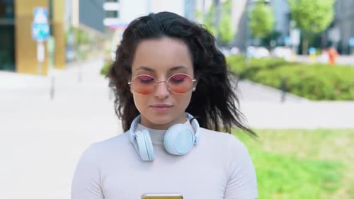 Happy Young Woman with Smartphone Standing in the Street