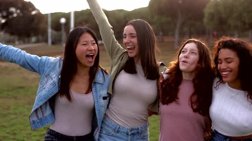 Female friends sharing genuine moment of joy, laughing and hugging during outdoor gathering, celebra
