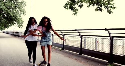 Teens skateboarding together down urban sidewalk