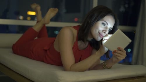 Woman Relaxing and Using Tablet Device at Night
