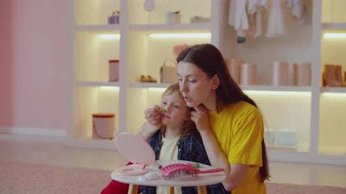 Joyeuse et jolie mère et jolie petite fille faisant du maquillage de fête à la maison