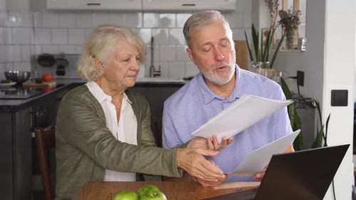 Senior Couple Reviews Documents in Kitchen