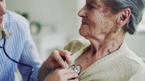 A Health Visitor Examining a Senior Woman with a Stethoscope at Home