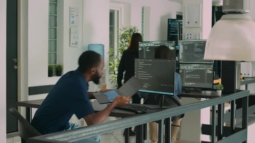 Desenvolvedor afro-americano usando laptop para escrever código e exibir informações do sistema