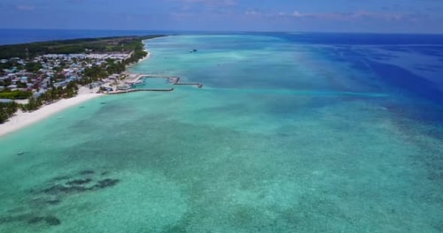 Panoramic aerial push in towards exquisite Maldives coast. Crystal clear water, white beach and lush