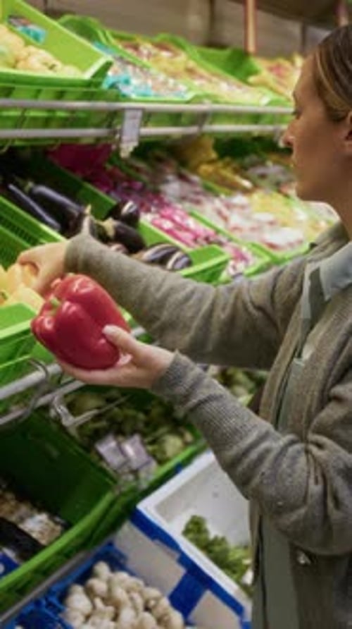 Female Shopper Examining Yellow and Red Bell Peppers while Choosing Vegetables