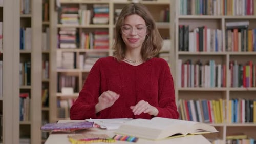 A young beautiful caucasian female student studying in the library—medium shot.