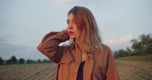 Beautiful female blonde model standing on a plowed field