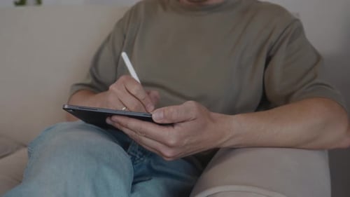 Man Drawing on Tablet with Pen Indoors
