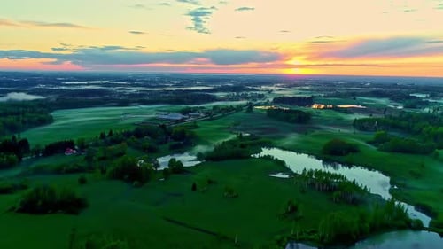 Sunset over verdant landscape with lakes. Aerial backward