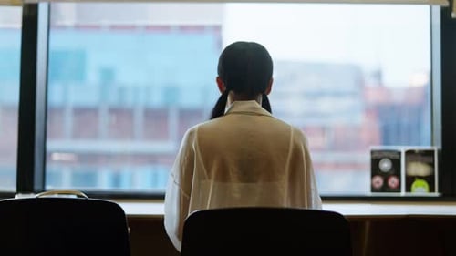 Woman Sitting At A Desk Near A Window