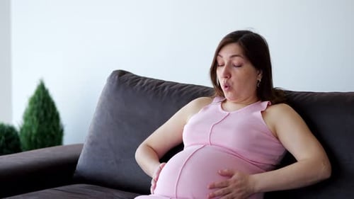 беременная женщина держится за живот с тревожным выражением лица