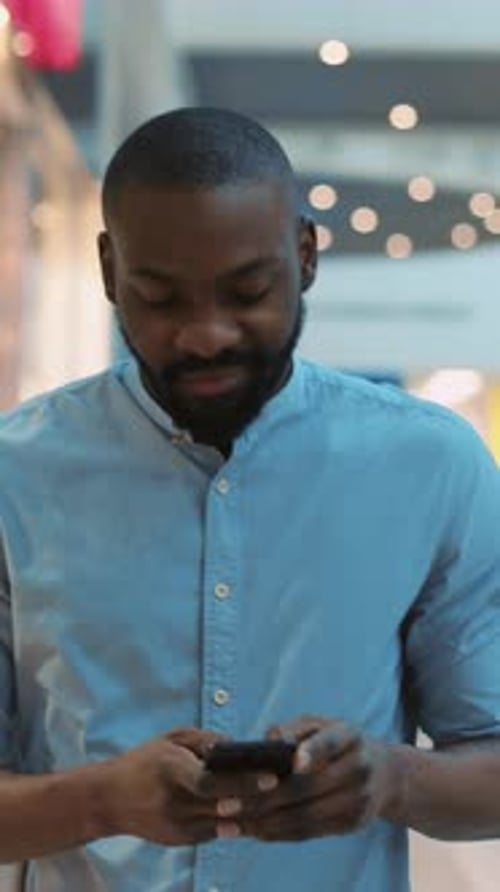 A Man is Focused on His Smartphone in a Modern Urban Setting Reflecting Contemporary Lifestyle