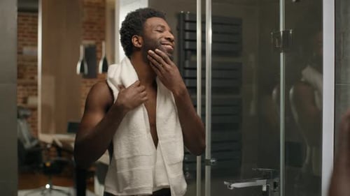 Smiling Man with Towel Looks in Mirror