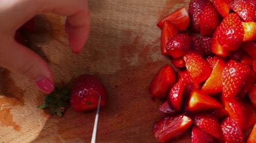 Woman Cuts Ripe Strawberries on Wooden Cutting Board