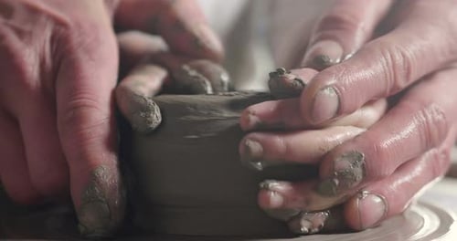 Hands Guiding Child Shaping Clay Pottery