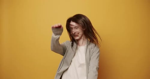 Woman Dancing Energetically Against Yellow Background