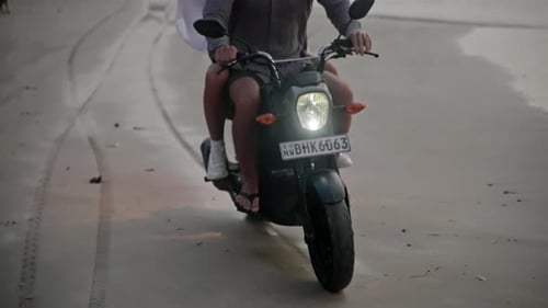 Tilt Transition From Sandy Beach to Couple Riding a Motorbike on Sea Shore Splashing Water in
