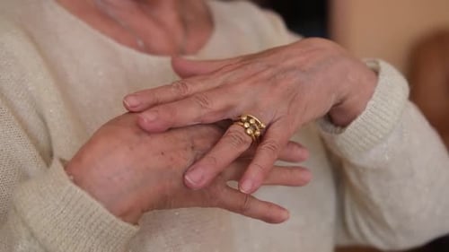 Elderly Woman Rubbing Hand with Joint Pain