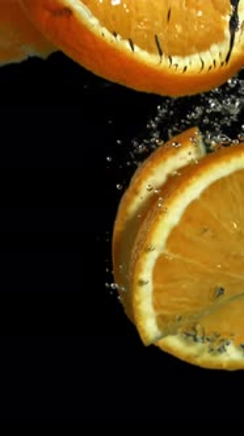 Orange Slices Falling Under Water on a Black Background Filmed on a Highspeed Camera at 1000 Fps
