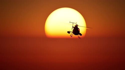 Silhouette Helicopter Flying Across Golden Sunset