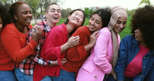 Young multiracial women embrace friendship and joyful laughter in London park