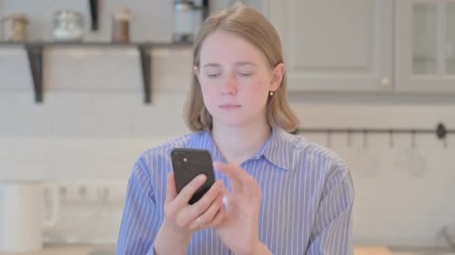 Young Woman Using Smartphone in Bright Kitchen