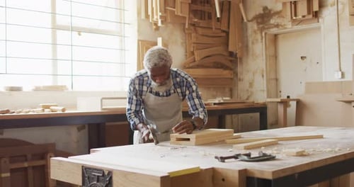 African american male carpenter hammering nails into the wood at a carpentry shop
