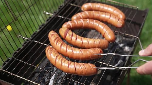 Tasty juicy sausages grilling. Barbecue grill cooking outdoors. Hot dog sausages are turning