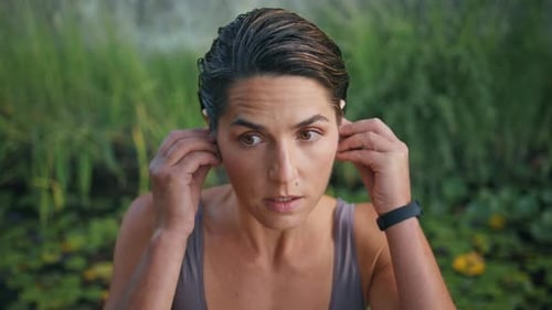Woman Puts in Earbuds Preparing for Workout