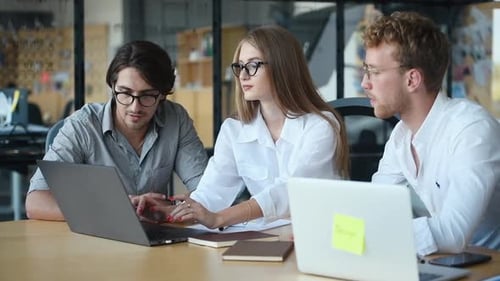 Young Adults Collaborate on a Laptop in an Office