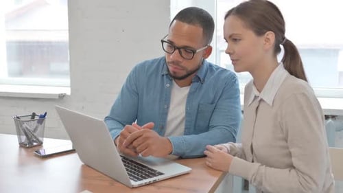 Man and Woman Collaborating on Laptop in Office