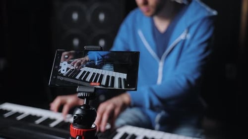 A Professional Piano Player is Using His Mobile Phone to Record His Performance