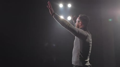 Man on stage gesturing with arms