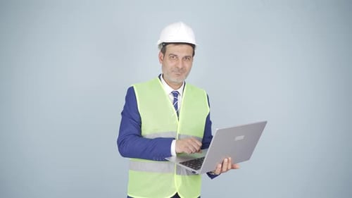 Engineer holding laptop laughing at camera.