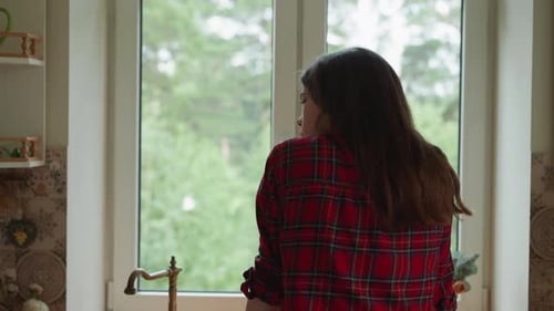 Woman Looking Out Window in Kitchen