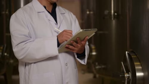 Vigneron professionnel contrôlant le processus de fabrication et la qualité du vin dans une usine vinicole