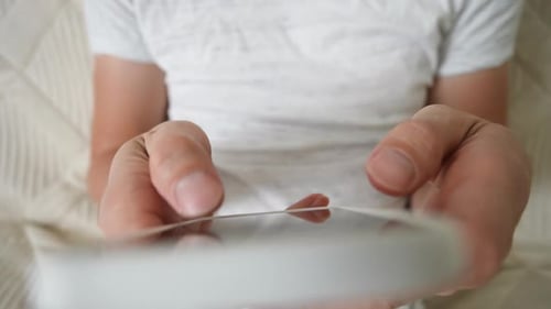 Highangle View of Unrecognizable Young Adult Man Using Cellphone for Writing Send Message Sitting on