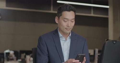 Asian Businessman Working on Smart Phone in Office
