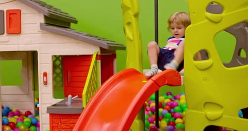Enfant en bas âge glissant dans une salle de jeux colorée