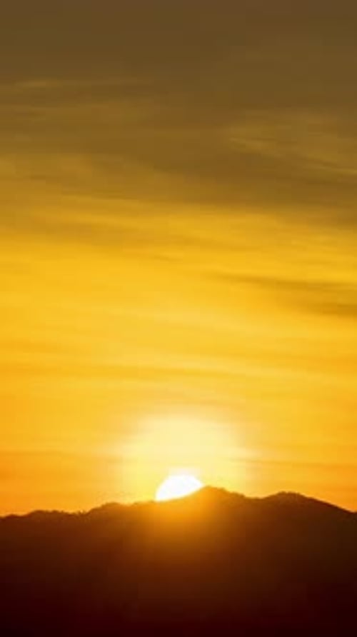 Zeitraffer eines dramatisch Sonnenaufgangs mit orangefarbenem Himmel an einem sonnigen Tag.