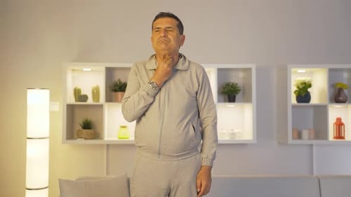 Man Touching Sore Throat and Yawning Indoors